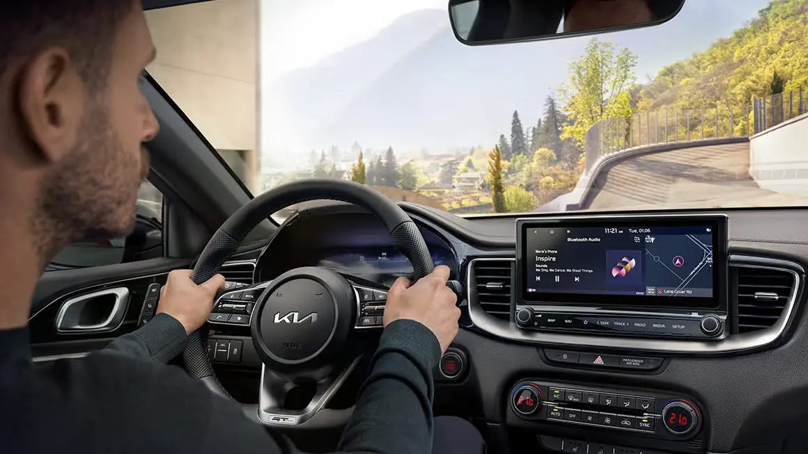 Ein Fahrer steuert einen Kia Ceed mit Blick auf das Navigationsdisplay.