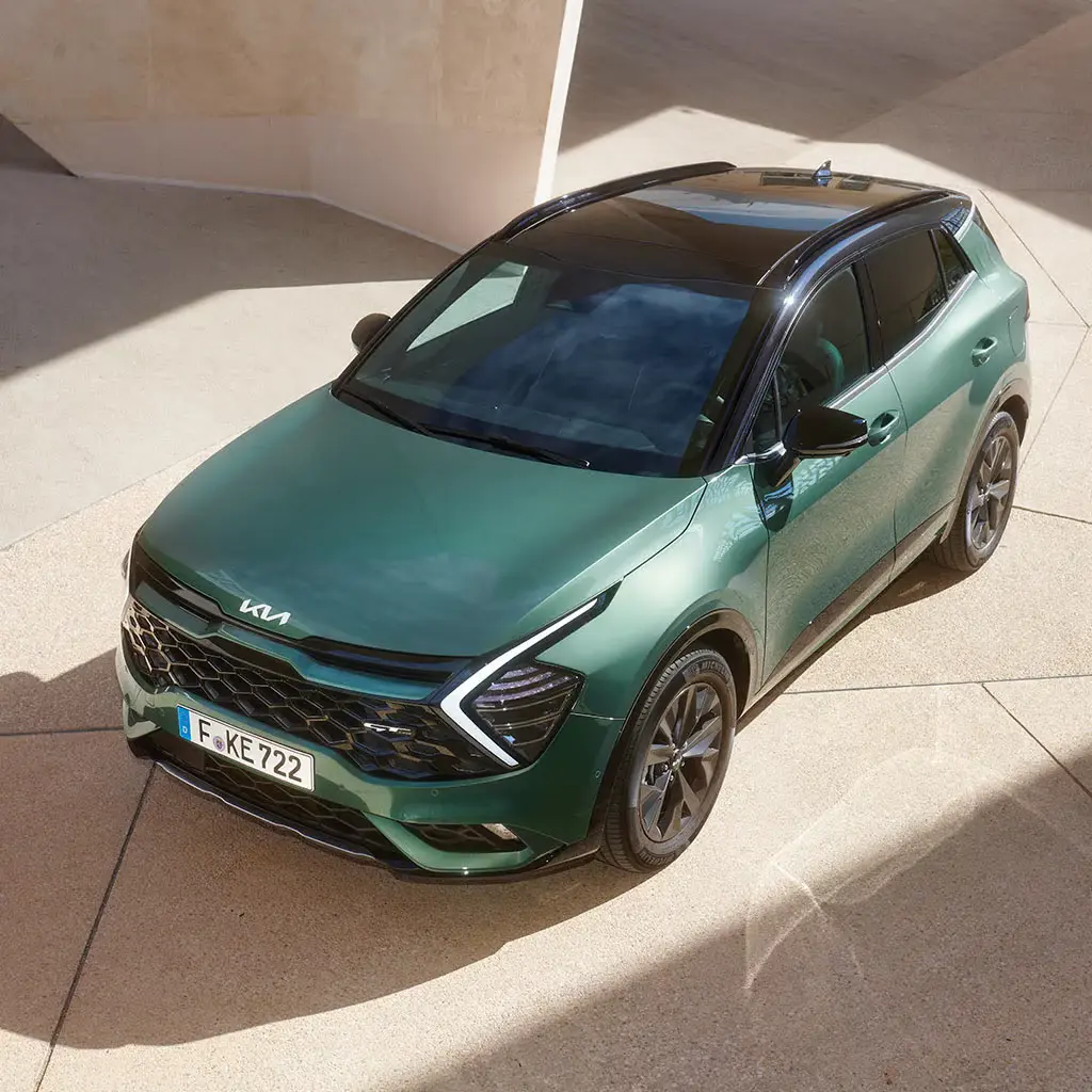 Ein grüner Kia Sportage SUV steht auf einem gepflasterten Platz.