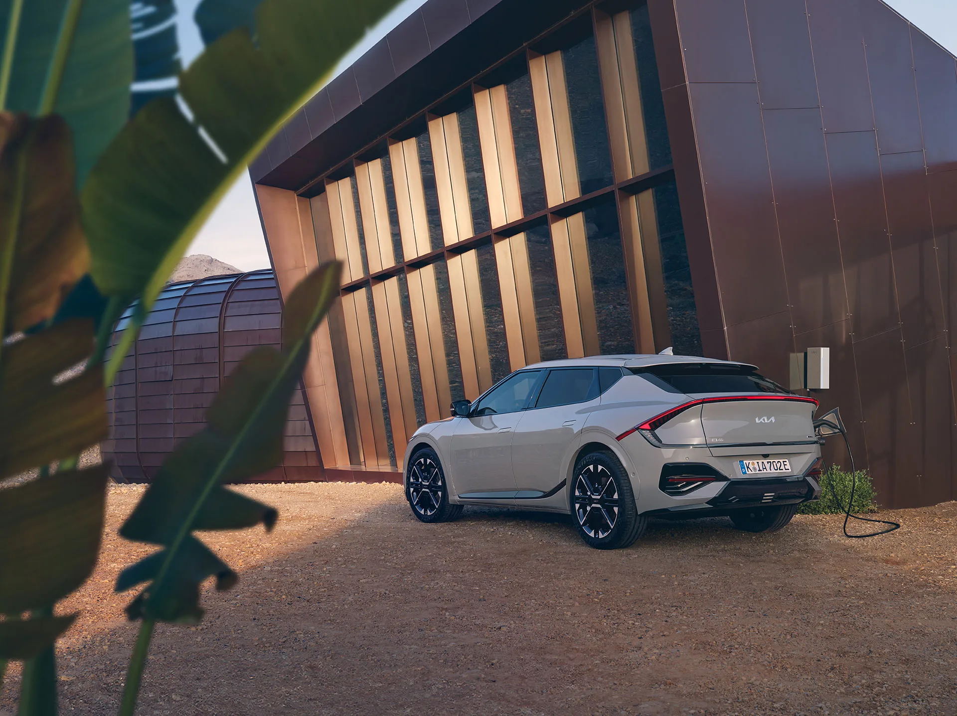 Ein Kia EV6 wird an einer Ladestation in einer modernen, architektonischen Umgebung aufgeladen.