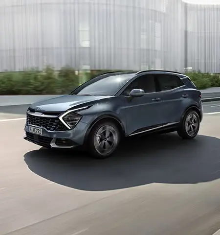 Ein grauer Kia Sportage fährt auf einer Straße.