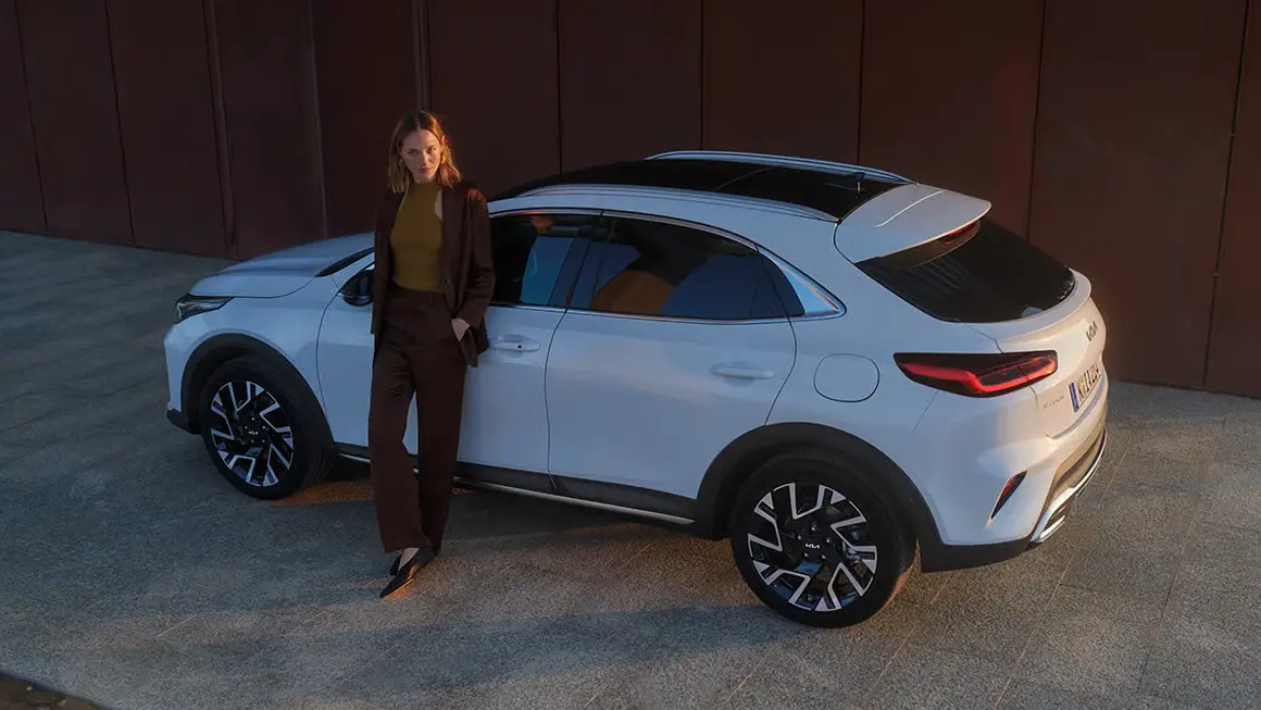 Eine Frau lehnt an einem weißen Kia XCeed.