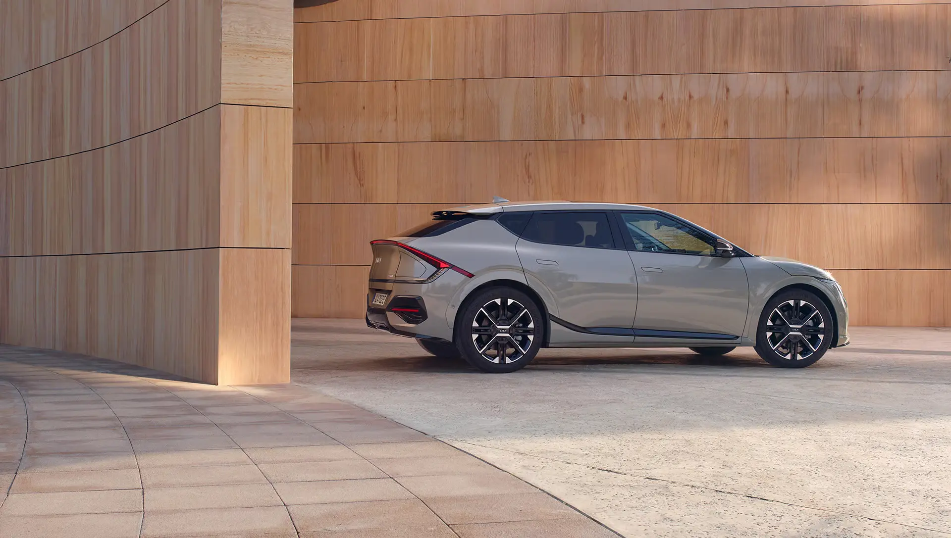 KIA EV6 in Grau, seitlich geparkt vor einer Holzwand.