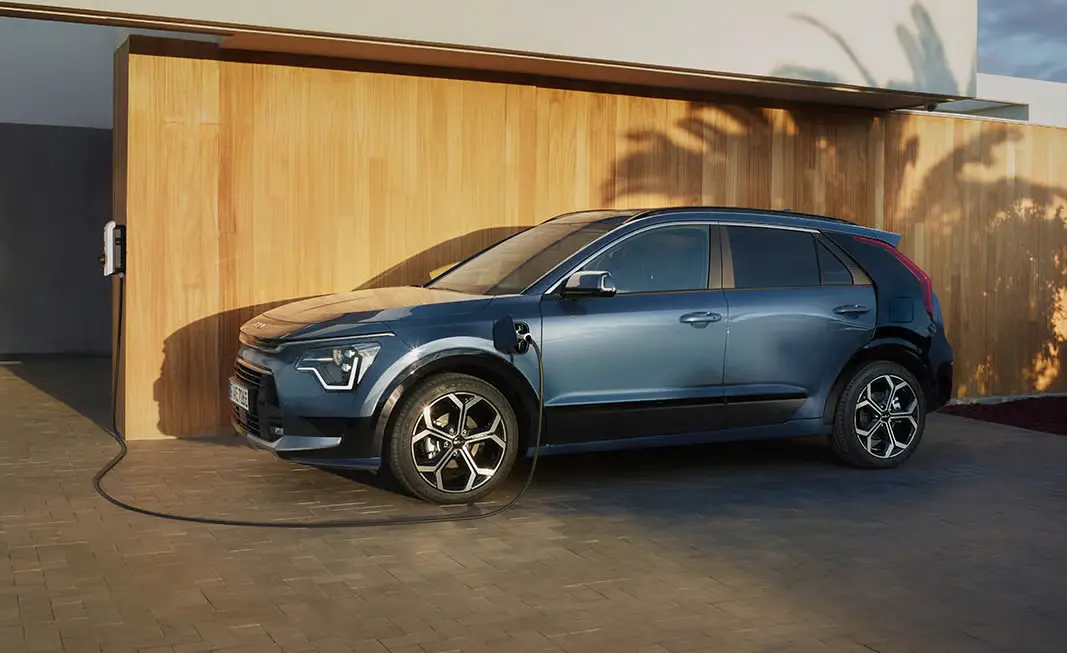 2-slider-kia_niro Ein blauer Kia Niro wird an einer Ladestation aufgeladen.