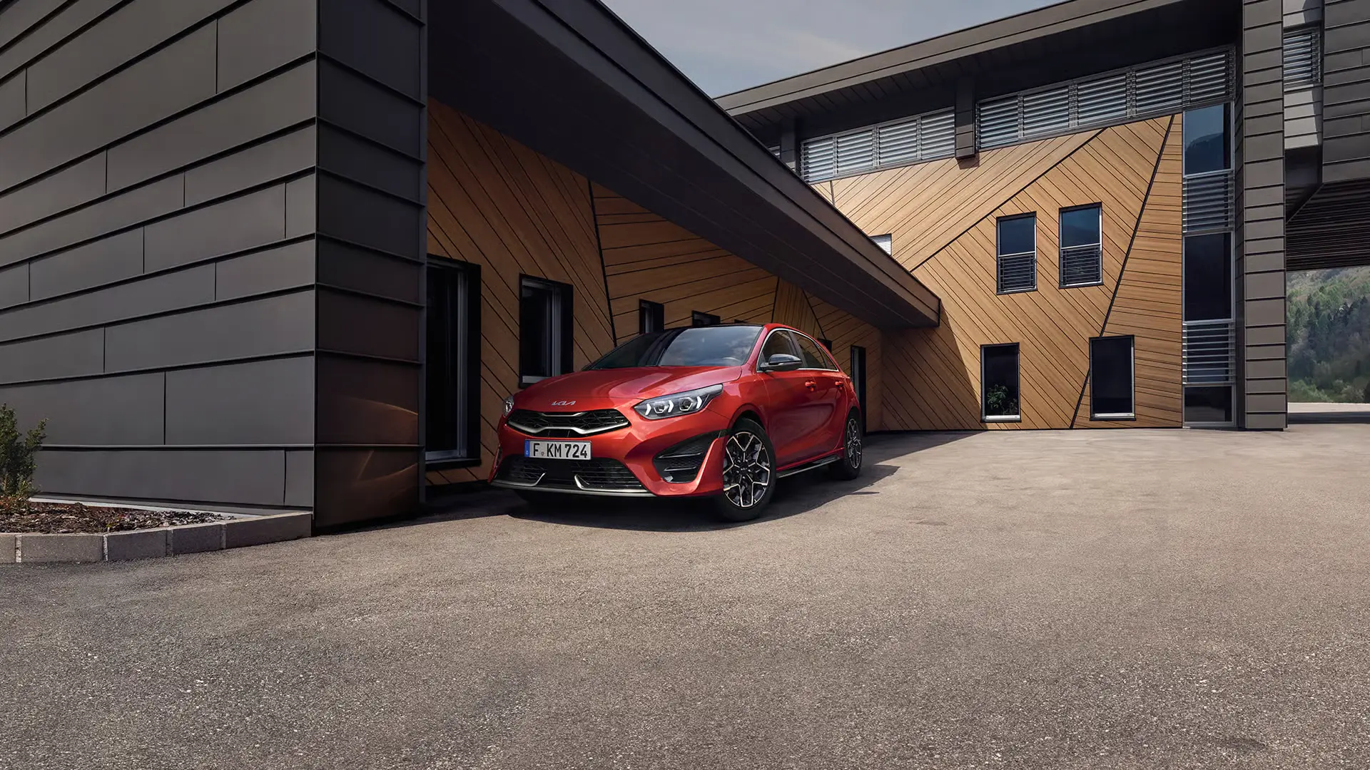 Ein roter Kia Ceed steht vor einem modernen Gebäude.