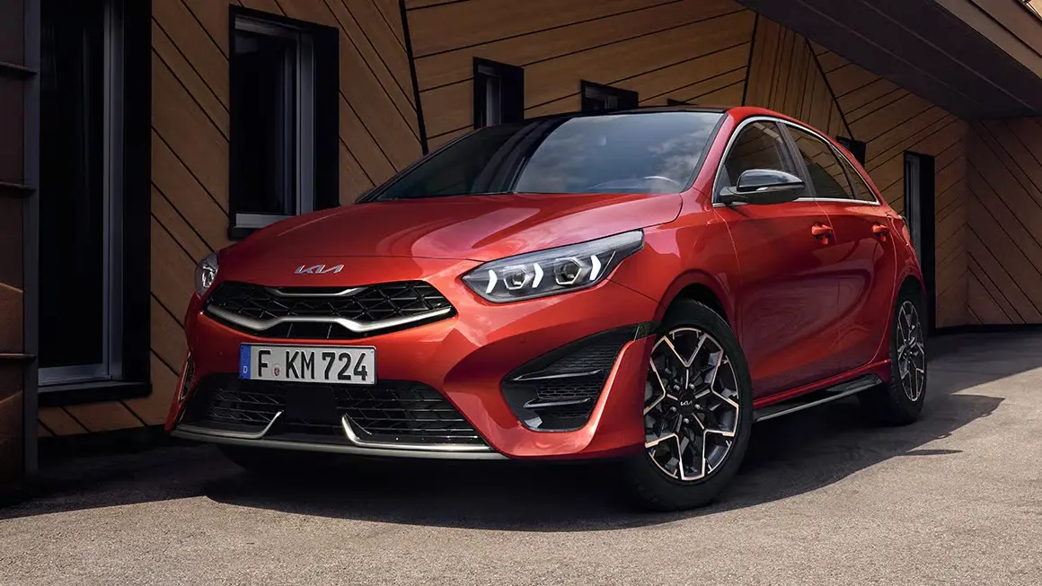 Ein roter Kia Ceed steht vor einem modernen Gebäude.