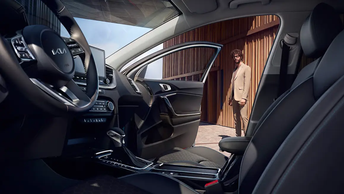 Innenansicht eines Kia Ceed Sportswagon mit geöffneter Fahrertür, ein Mann steht draußen.