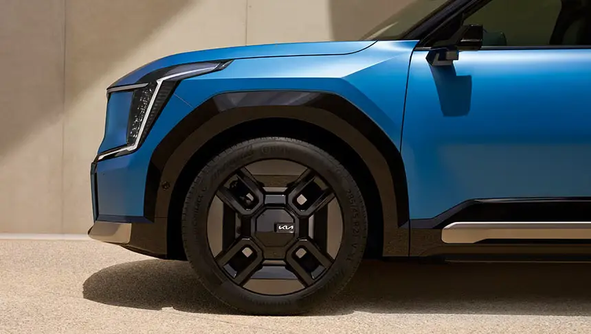 Ein blauer Kia EV9, seitliche Nahaufnahme des Vorderreifens und Kotflügels.