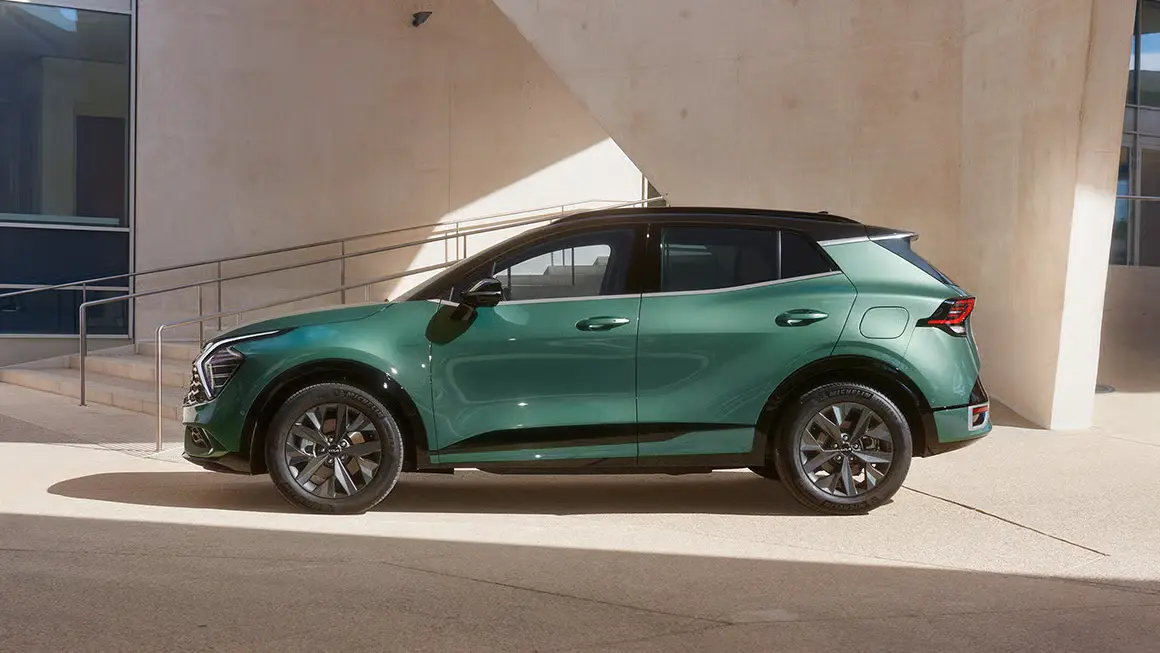 Ein grüner Kia Sportage steht seitlich vor einem modernen Gebäude.