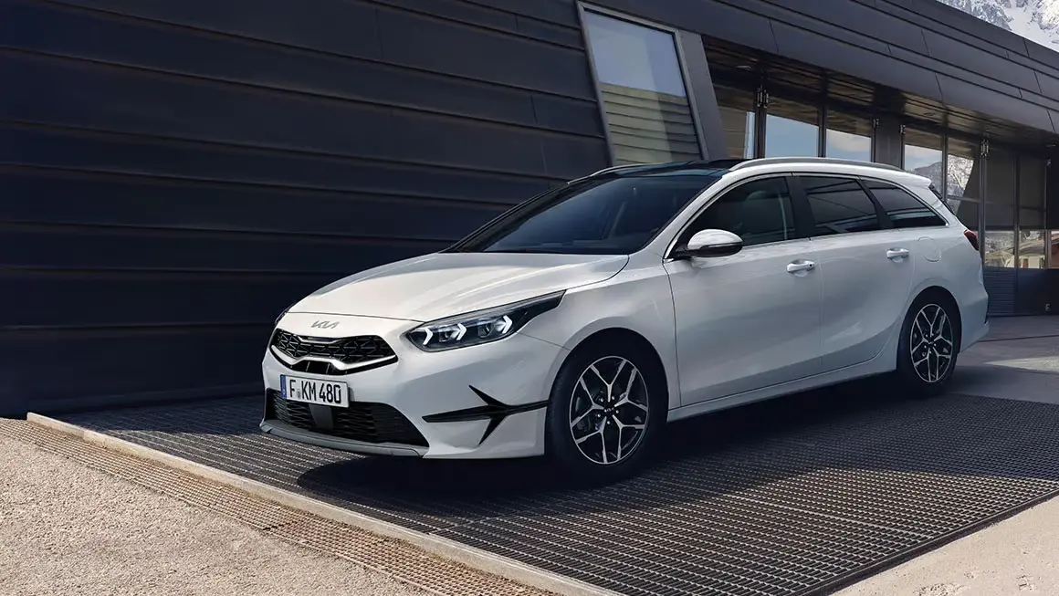 Ein weißer KIA Ceed Sportswagon steht vor einem modernen Gebäude.