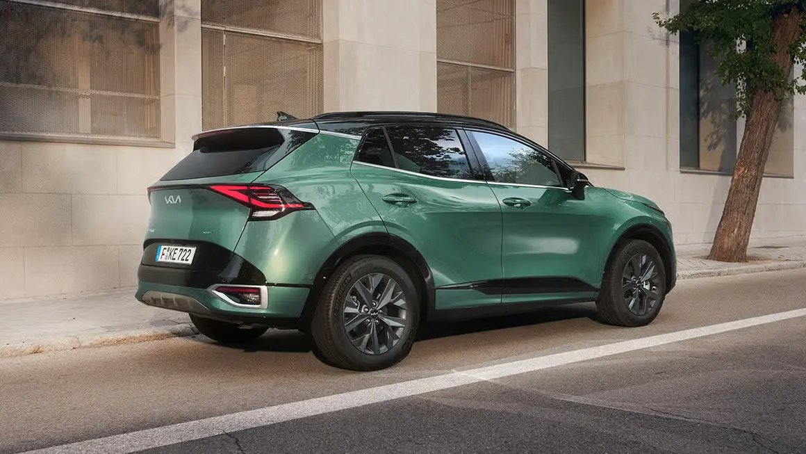 KIA Sportage in grüner Farbe, geparkt auf einer Straße vor einem Gebäude.