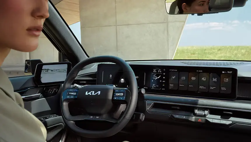 Innenansicht eines Kia EV9 mit Fokus auf das Lenkrad und das digitale Armaturenbrett.
