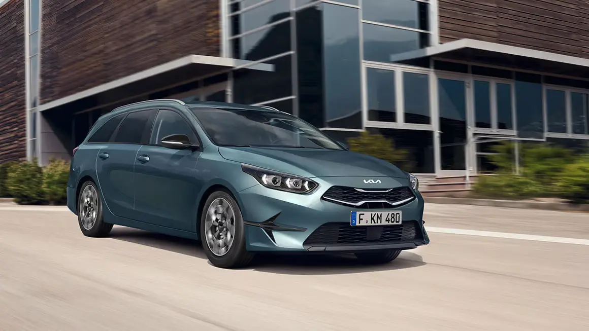 Kia Ceed SW in Bewegung vor einem modernen Gebäude.