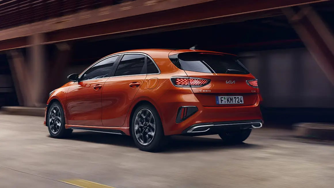 Ein orangefarbener Kia Ceed fährt auf einer Straße.