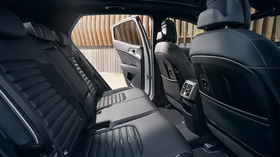 Innenraum eines Kia Sportage mit geöffneter hinterer Tür und schwarzen Ledersitzen.