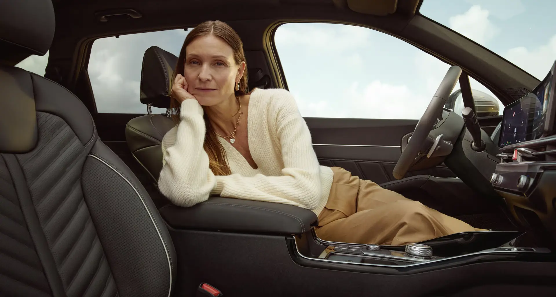 Eine Frau lehnt sich entspannt im Innenraum eines Autos zurück.