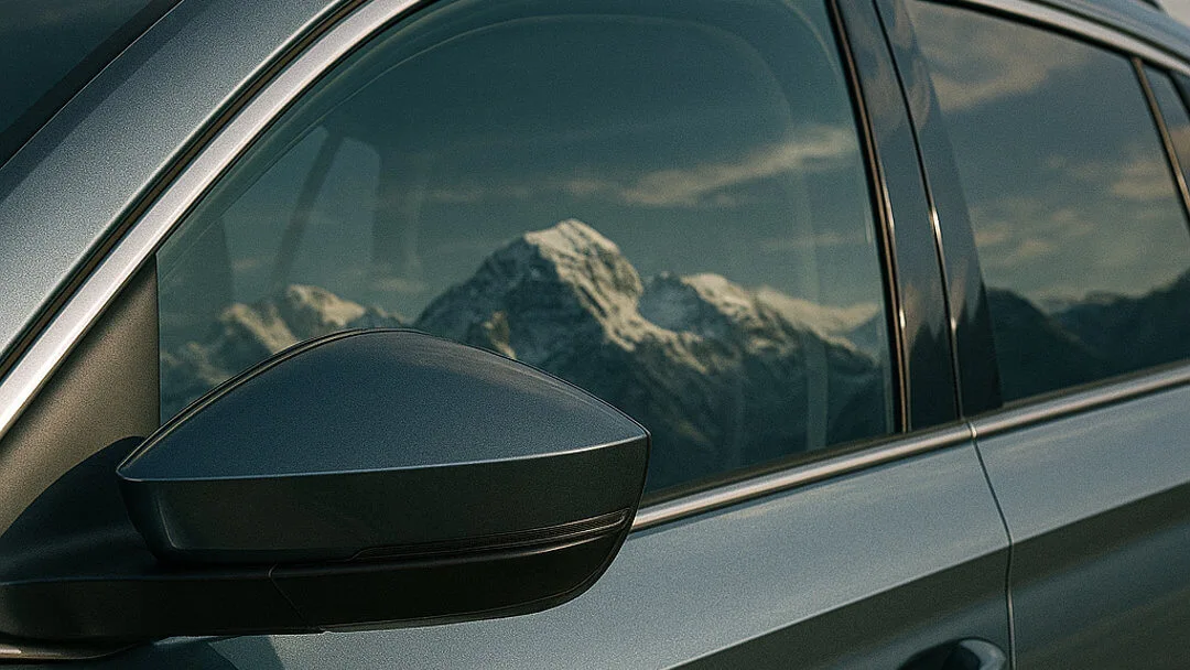 export-schweiz-text-bild-teaser Seitenspiegel eines Autos mit Berglandschaft im Hintergrund.