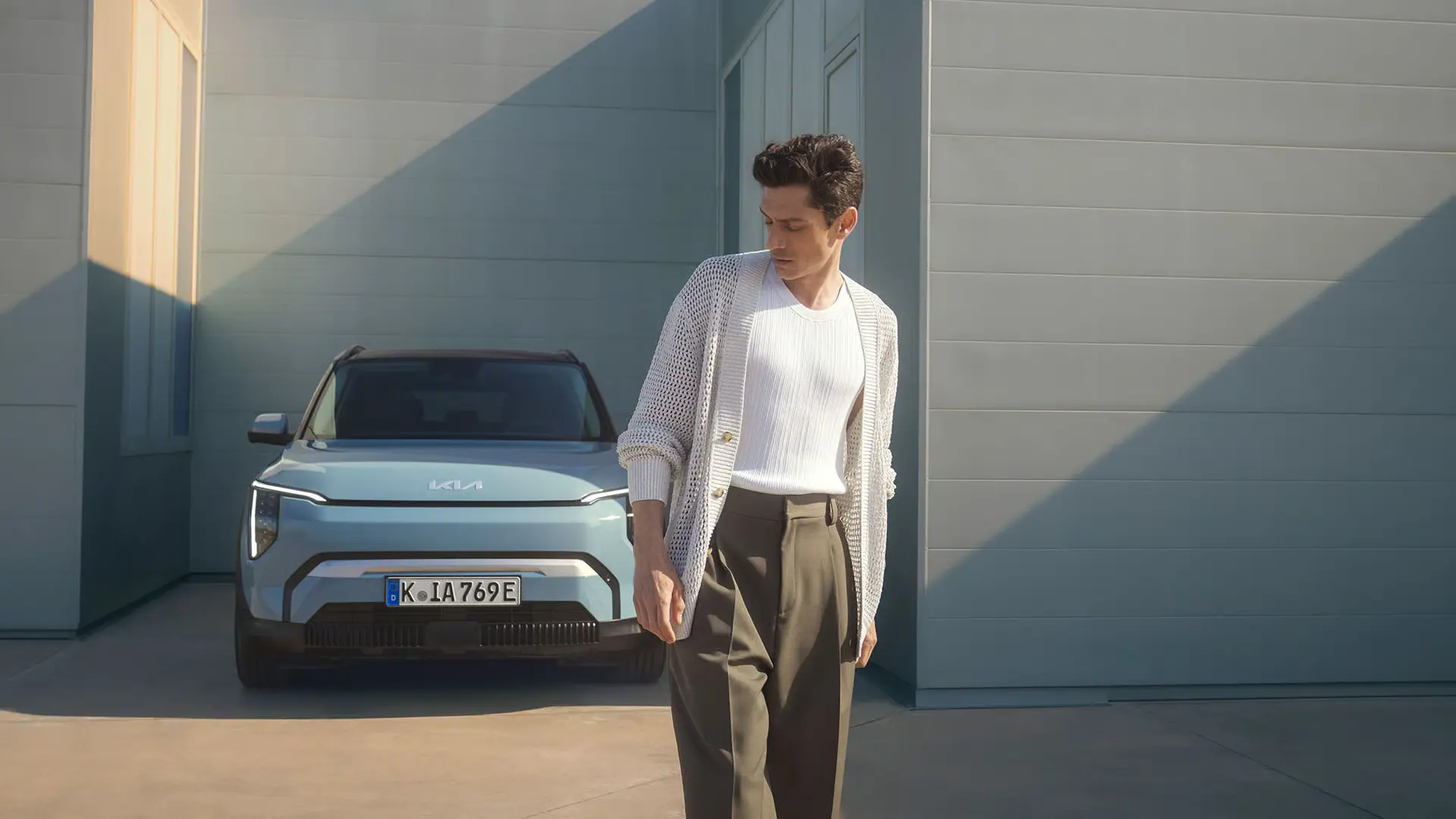 Ein Mann steht vor einem hellblauen Kia EV3.