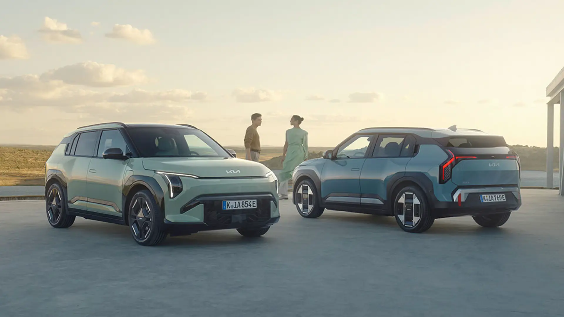 Zwei Kia EV3 Autos in einer offenen Landschaft bei Sonnenuntergang.