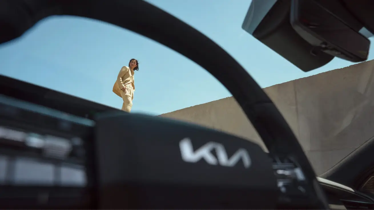 Blick durch das Lenkrad eines Kia EV9 auf eine Person, die draußen steht.