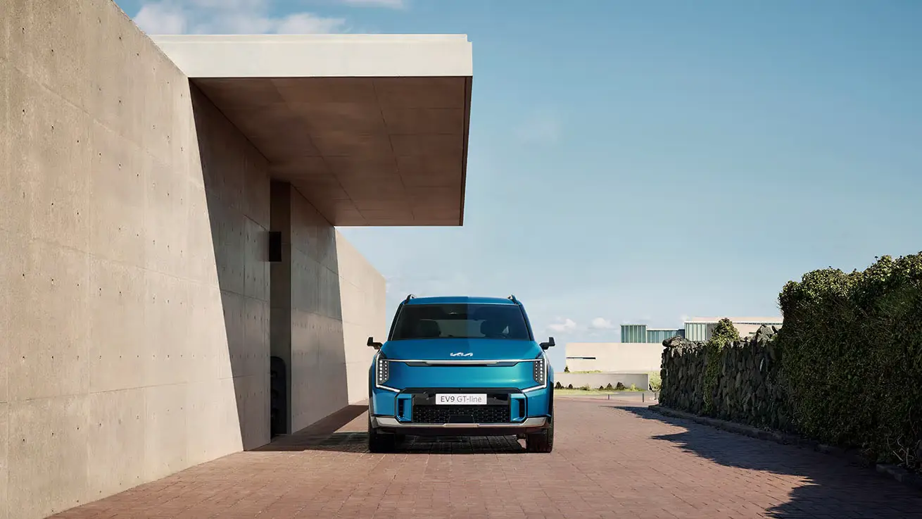 Ein blauer Kia EV9 steht in einer modernen, minimalistischen Umgebung.