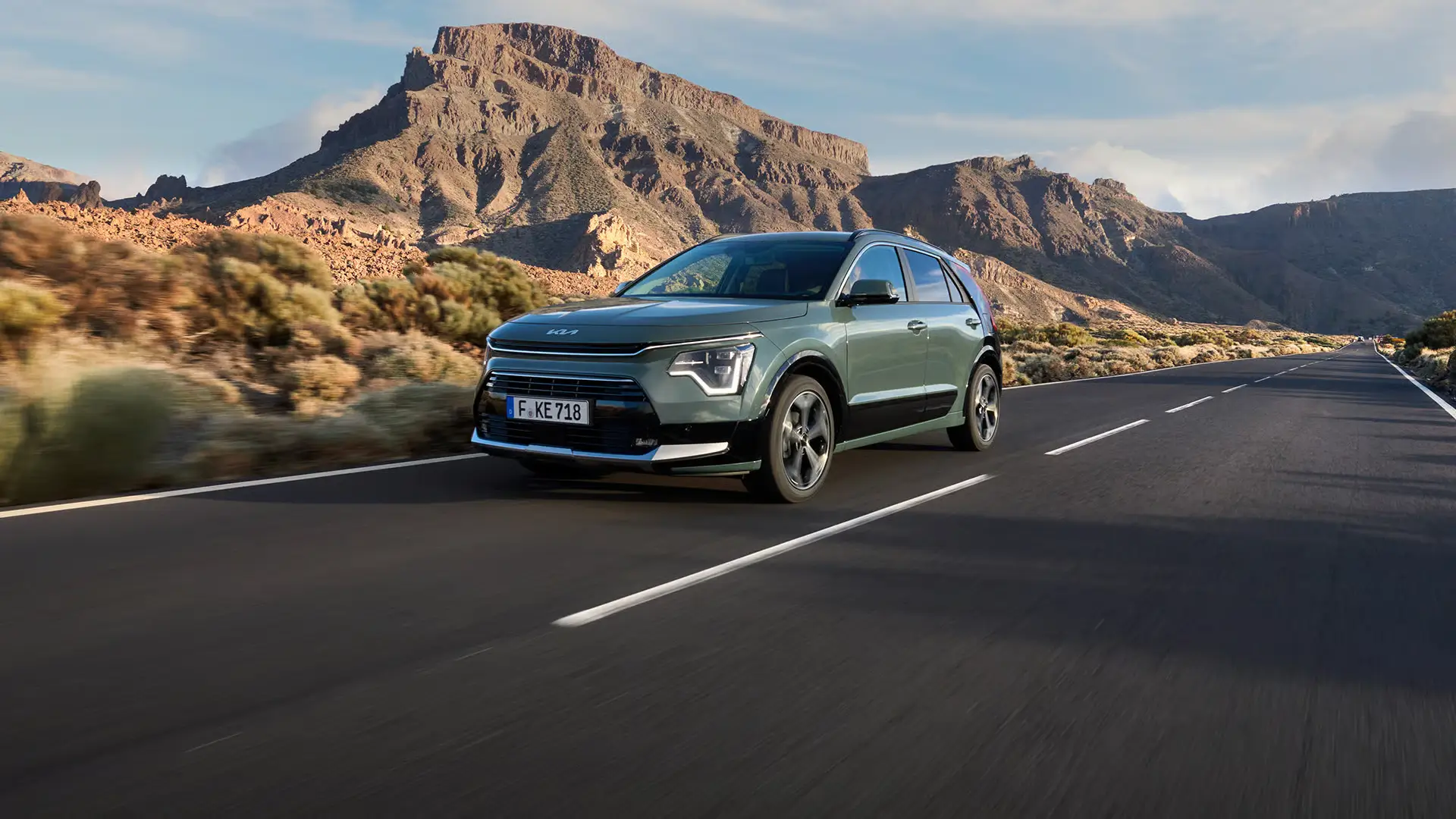 KIA Niro HEV fährt auf zweispuriger Landstraße durch felsige Berglandschaft.
