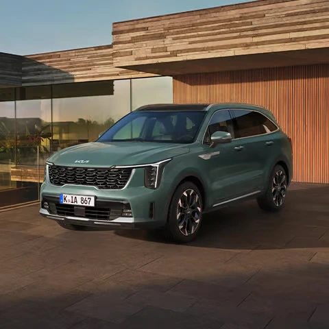Ein grüner Kia Sorento steht vor einem modernen Gebäude.