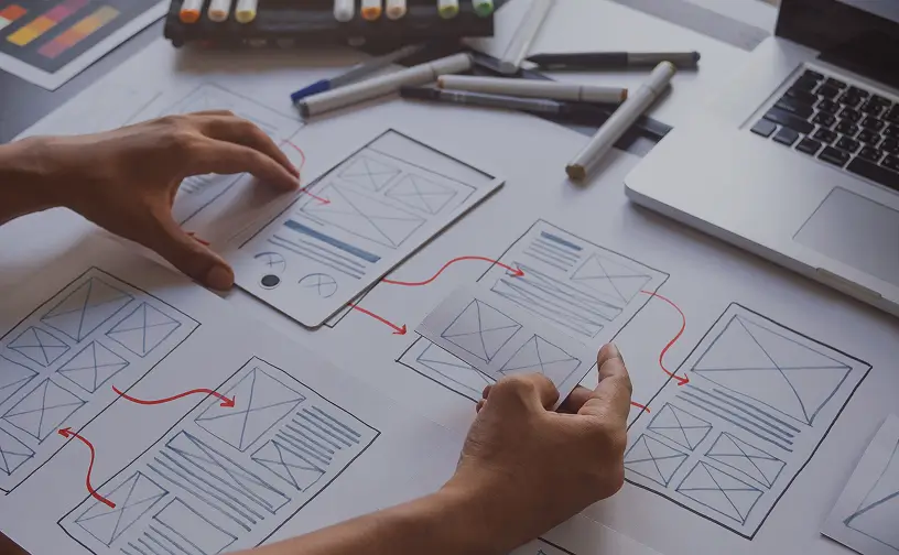 Person erstellt Wireframes für Webdesign auf Papier.