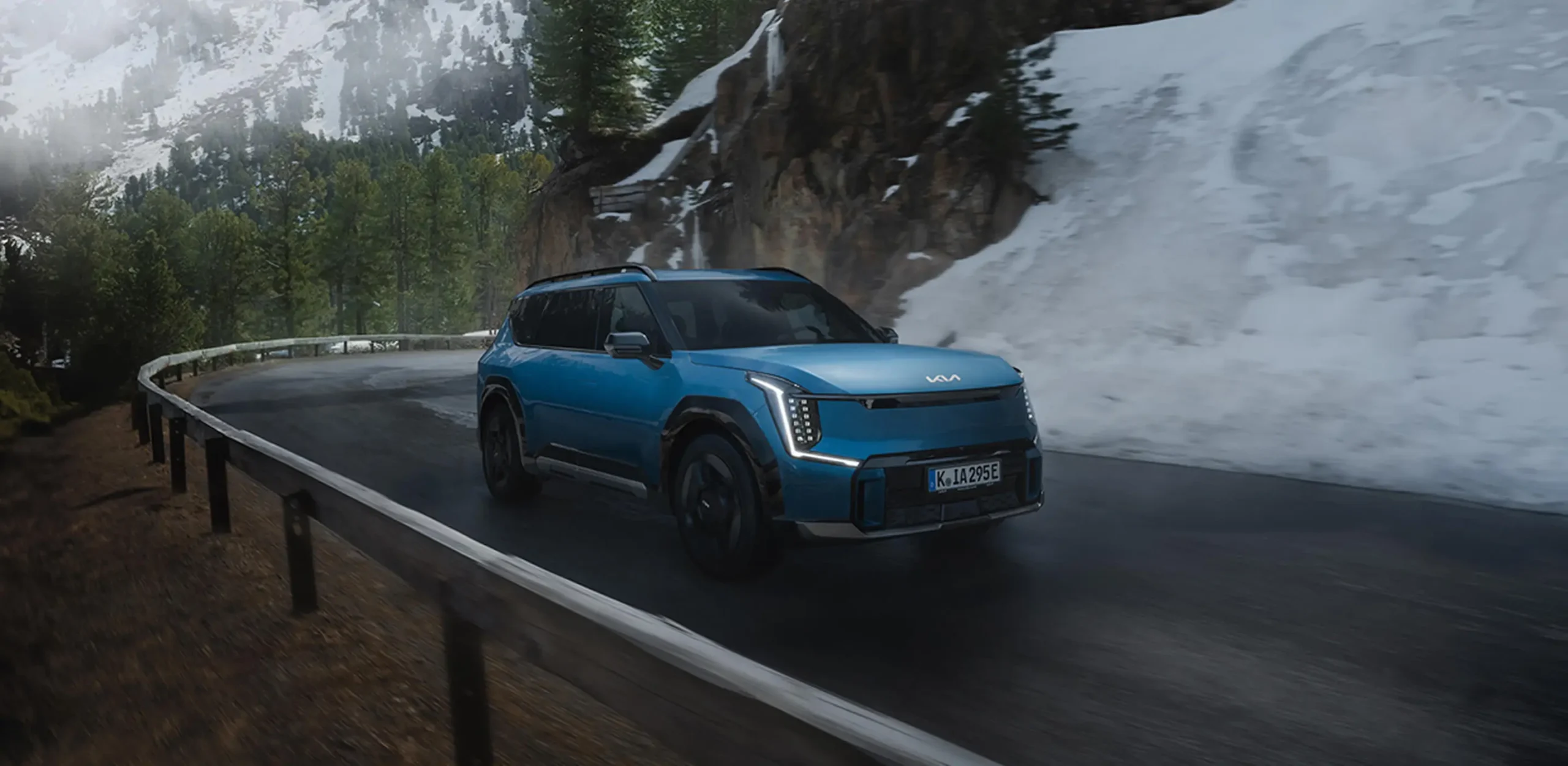 Automarkt2000_Service Winter Blauer Kia SUV fährt auf schneebedeckter Bergstraße.