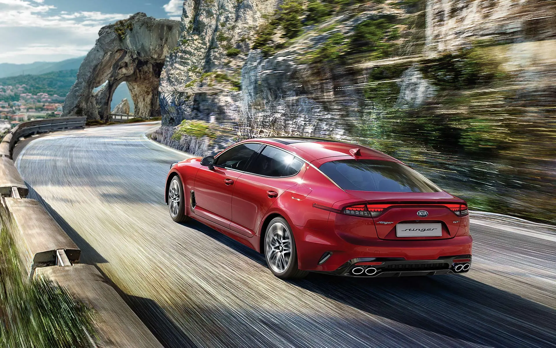 export-schweiz Ein roter Kia Stinger fährt auf einer kurvigen Bergstraße.