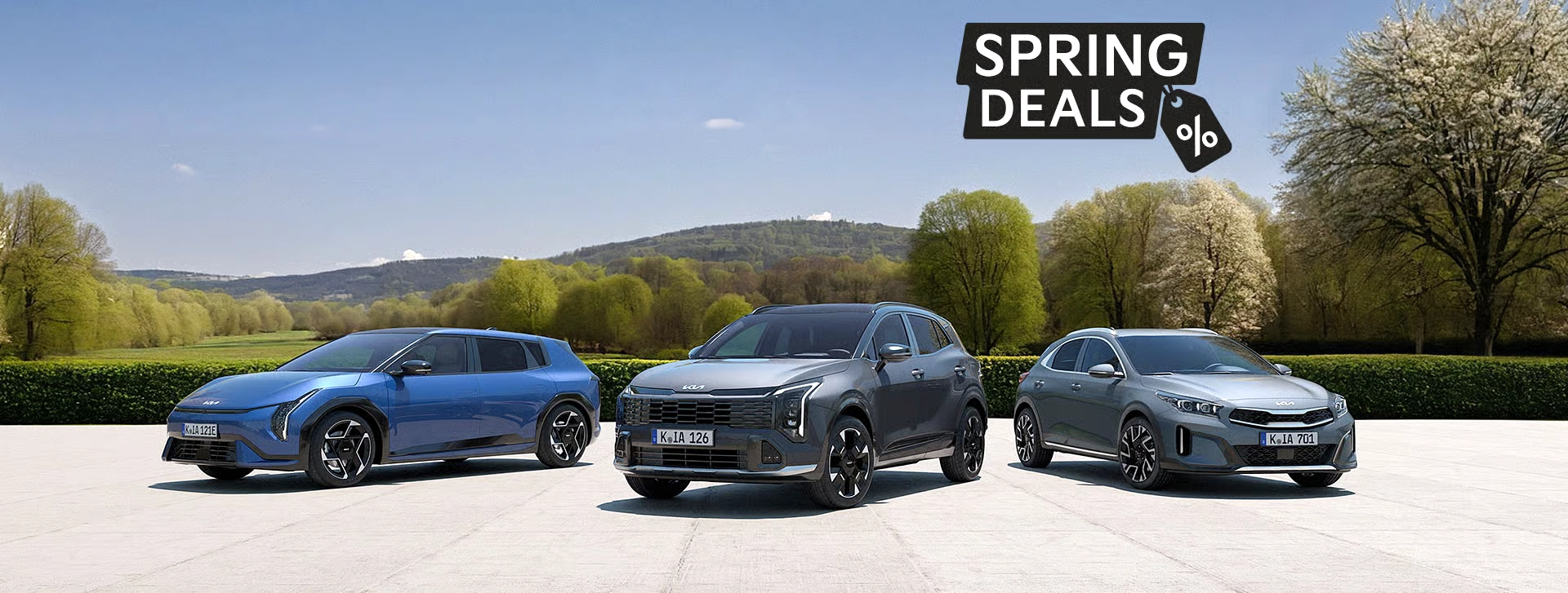Eine moderne Frühlingsszene mit drei aktuellen Kia-Modellen ein Crossover, ein SUV und eine Limousine – vor einer grünen Landschaft mit blühenden Bäumen